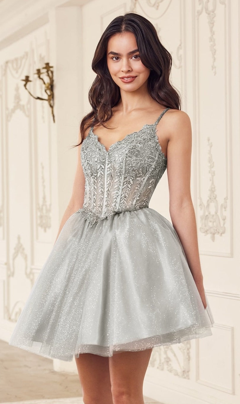A woman stands indoors wearing the Ladivine Embroidered Lace Homecoming Dress CD0236—a silver, glittery, sleeveless dress with a fitted bodice and delicate lace embroidery.